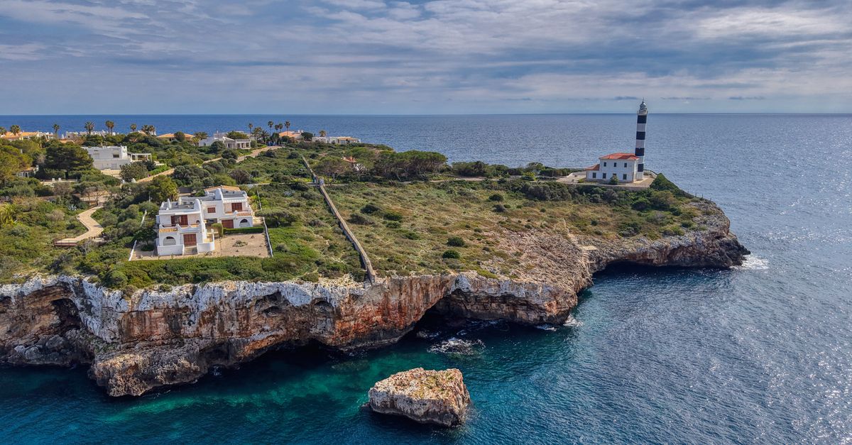 revisi-n-de-electrodom-sticos-en-mallorca-gu-a-completa Vista aérea panorámica de un faro en la costa rocosa de Mallorca, España, bajo un cielo parcialmente nublado.